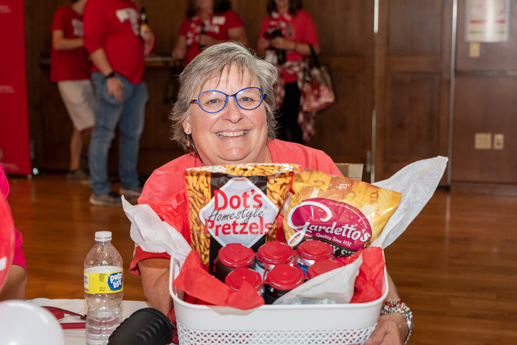 UWPharm-Tailgate_09172022_064 An alum poses with a raffle prize: a basket of snacks.