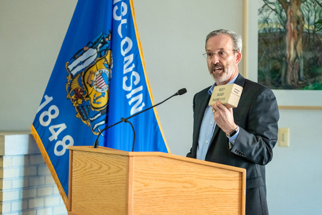 UWPhrmAward_2022_094 Dave Mott holding up a brick at podium