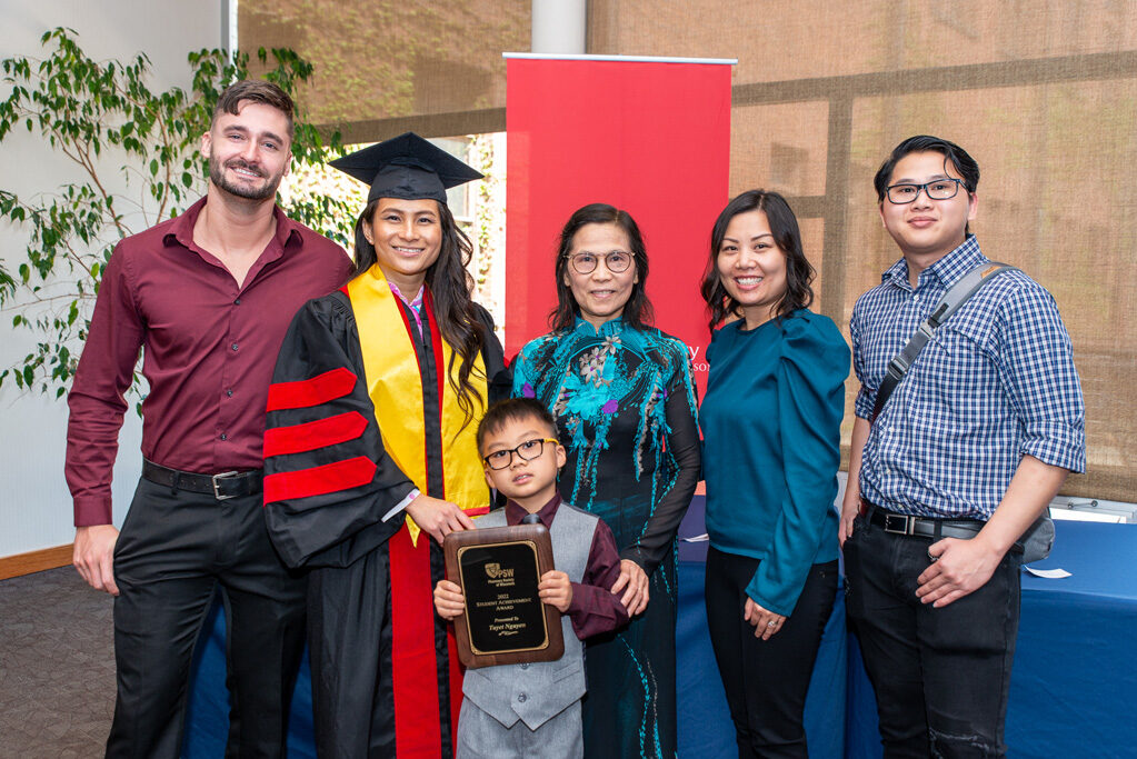 UWPhrmAward_2022_123 UW Pharm award recipient in her gown, surrounded by family