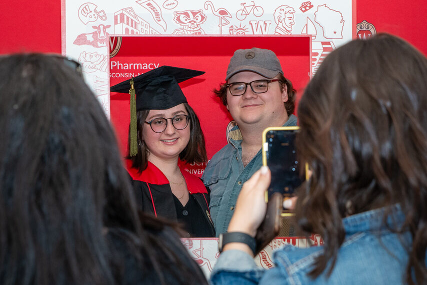 UWPhrmToxAw_2022_036 PharmTox student holding frame prop in front of red backdrop