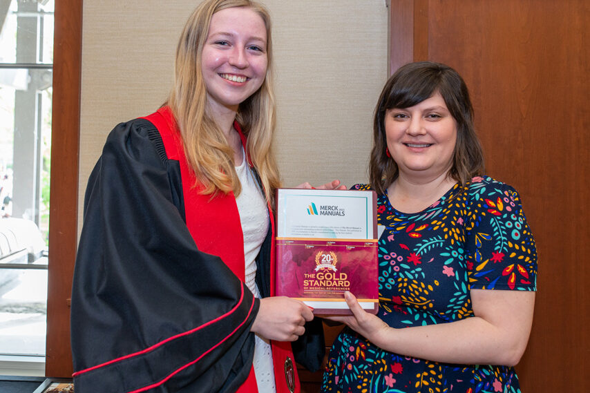 UWPhrmToxAw_2022_135 faculty member holding Merck Manual with graduate student