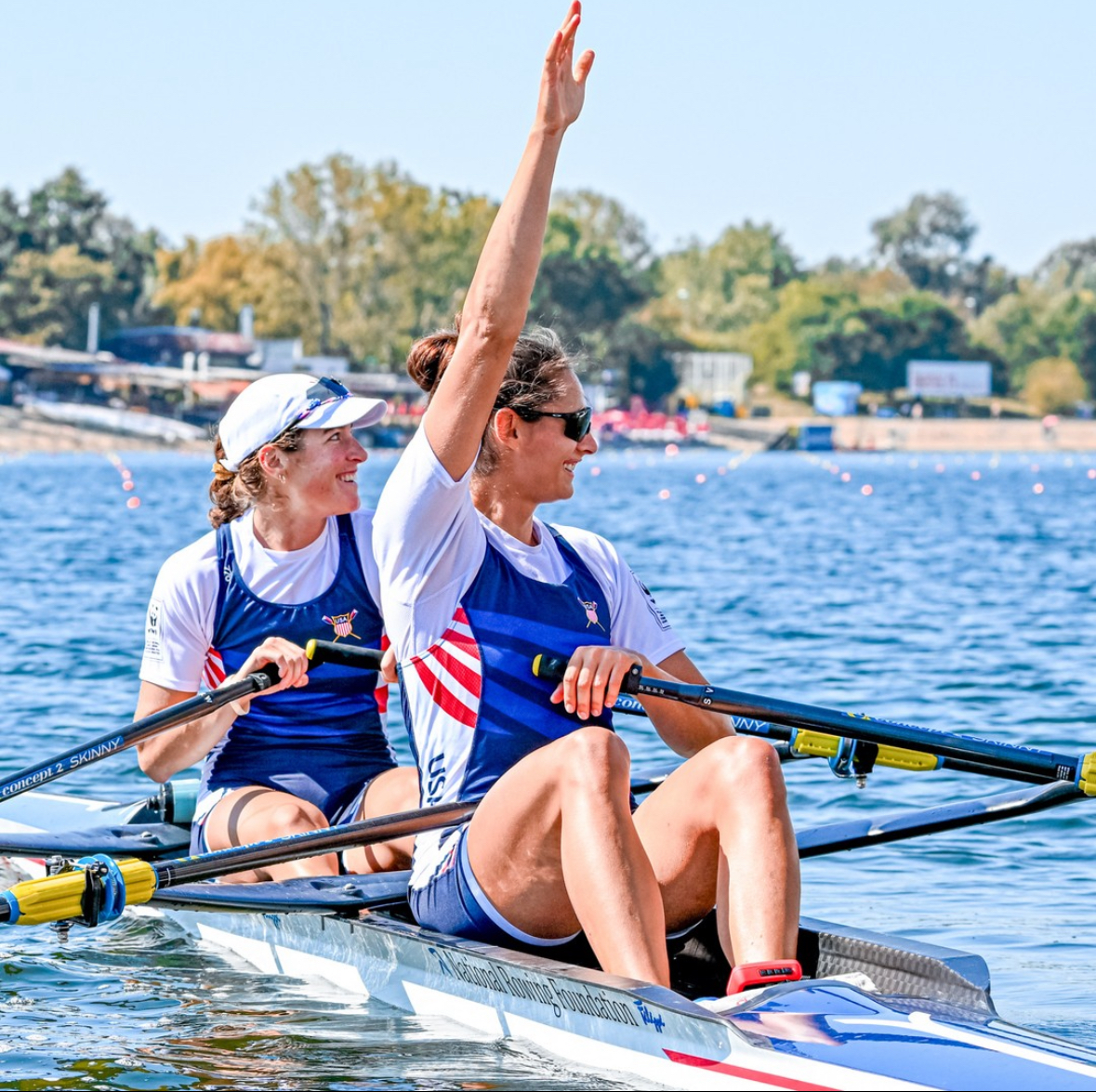 Sophia Vitas in a scull boat waving to shore wearing Team USA clothes.