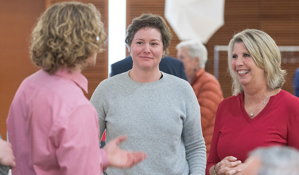 Riley Norman speaks with an attendee and Debra Fluno