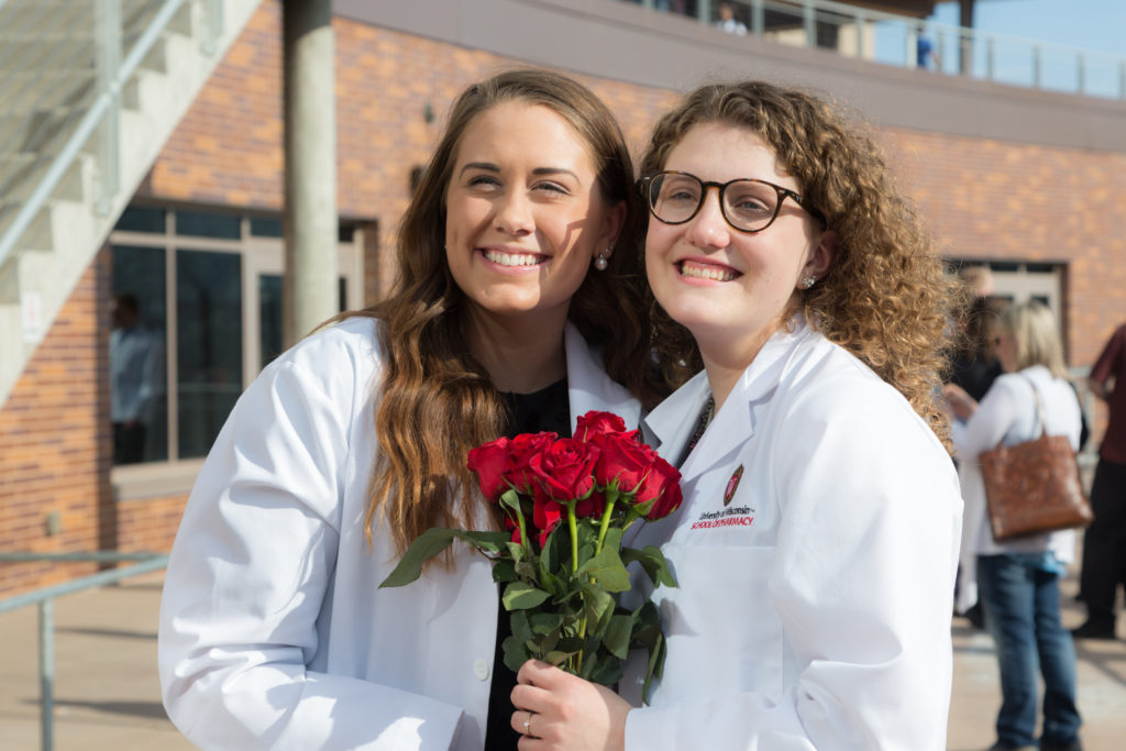 UW School of Pharmacy White Coat Ceremony 2018 Students together holding roses after White Coat Ceremony