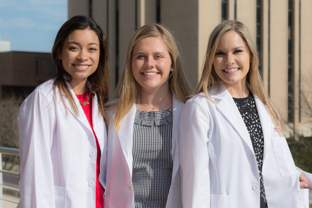 UW School of Pharmacy White Coat Ceremony 2018 PharmD students Haley Stafford (left), Alexandra Edinger (center), and Elizabeth Janet (right) pose outdoors following the 2018 White Coat Ceremony.