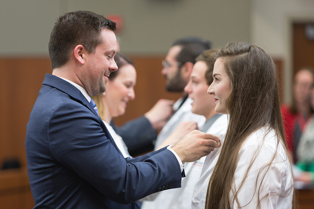 phar050219_012 A student accepts pin from Tyler Liebenstein, Pharmacy School Alumni.
