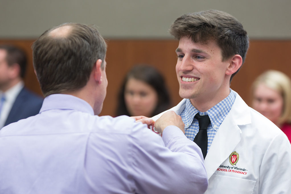 phar050219_018 Student accepts pin from Jason Law, alumni of the School.