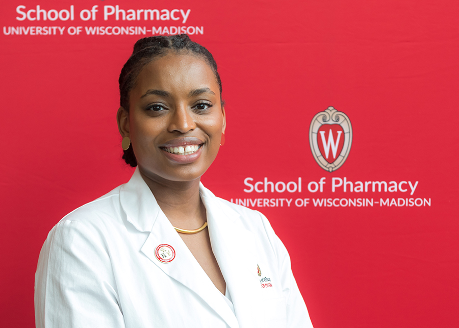 Maria Hill stands in front of a red School of Pharmacy photo background.