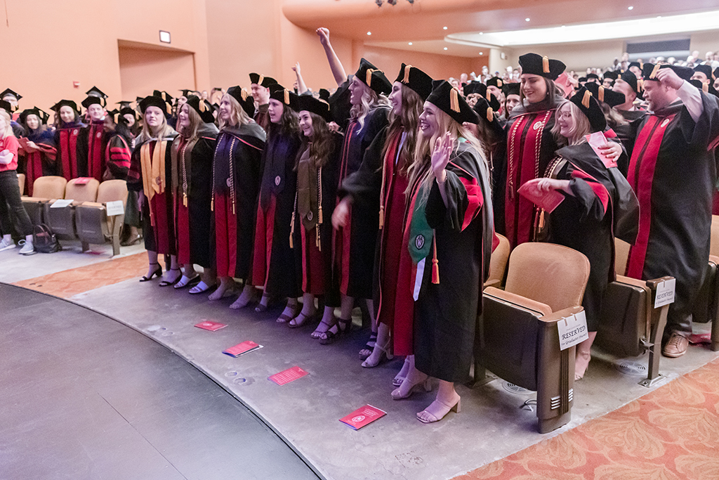 Inside, graduates are arm in arm at the end of the ceremony.