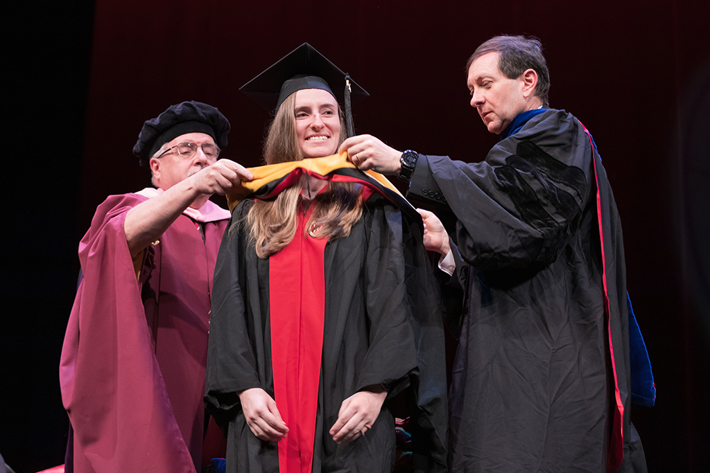 Assistant Dean Melgardt deVilliers and another professor putting the hood on a graduate student