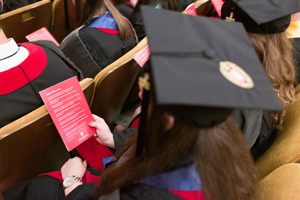View of a Class of 2022 PharmD graduate holding their program with the printed Oath of a Pharmacist