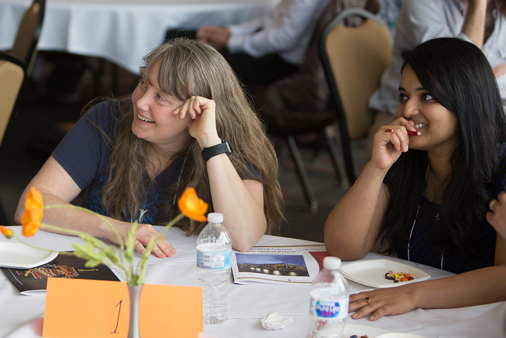 phar051818_130 Students, alumni, and faculty sitting around tables during trivia at the PharmSci retreat