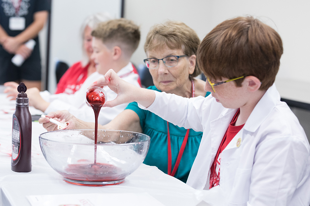 An attendee pours a red liquid into a bowl