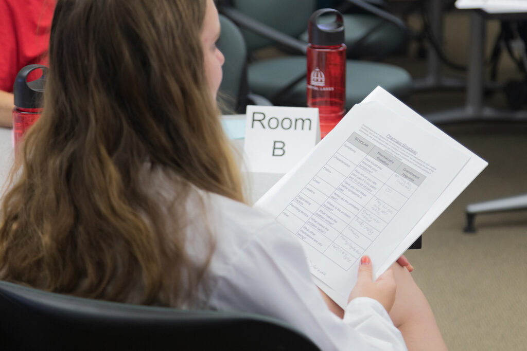 SoP Grandparents University 2023 A younger attendee holds worksheets in her hand