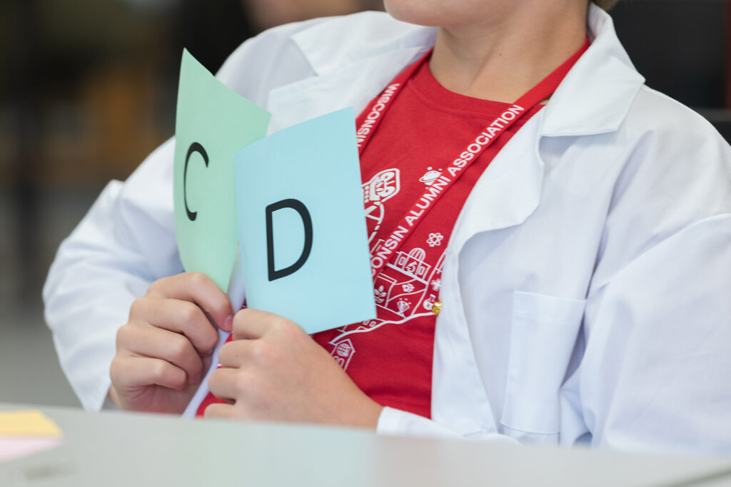 SoP Grandparents University 2023 A young attendee holds up papers, one with a letter C and one with a letter D