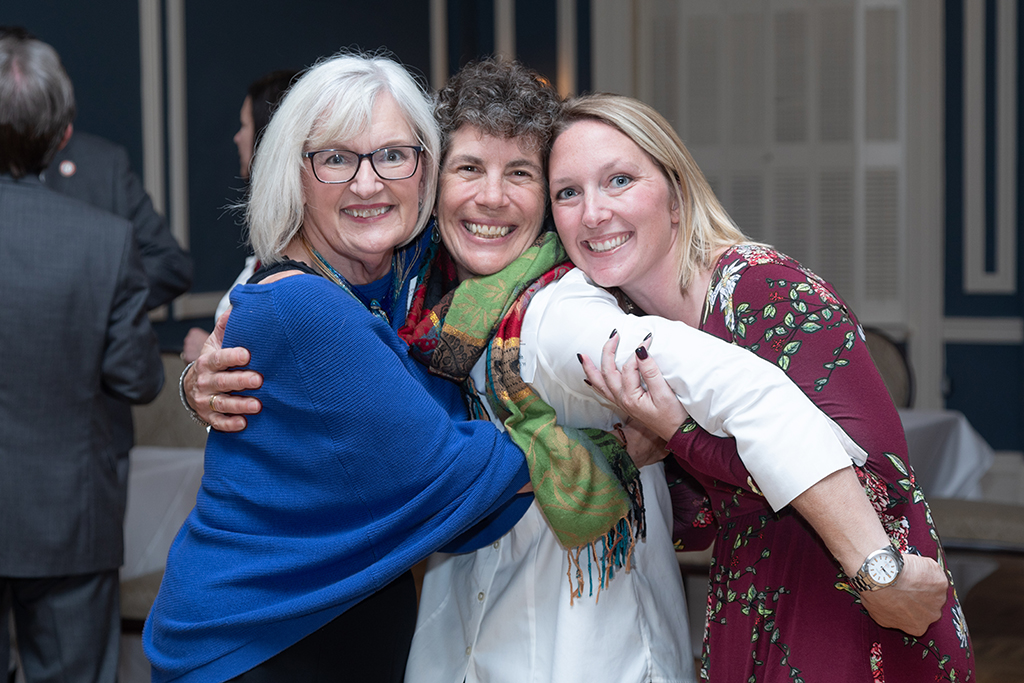 UW School of Pharmacy 2022 Citations of Merit Dinner & Awards Bonnie Fingerhut, Susan Stein, and another woman hug and smile at the camera.