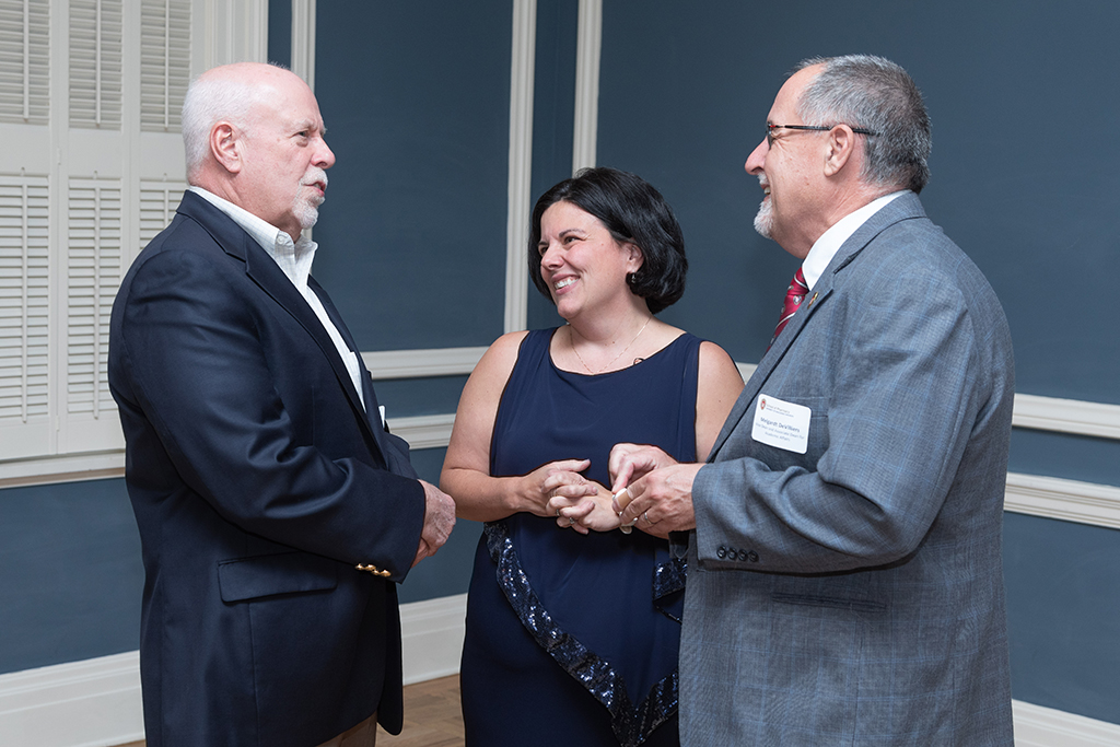 UW School of Pharmacy 2022 Citations of Merit Dinner & Awards Michelle Farrell, Mel de Villiers, and Bill Mellon smile in conversation.