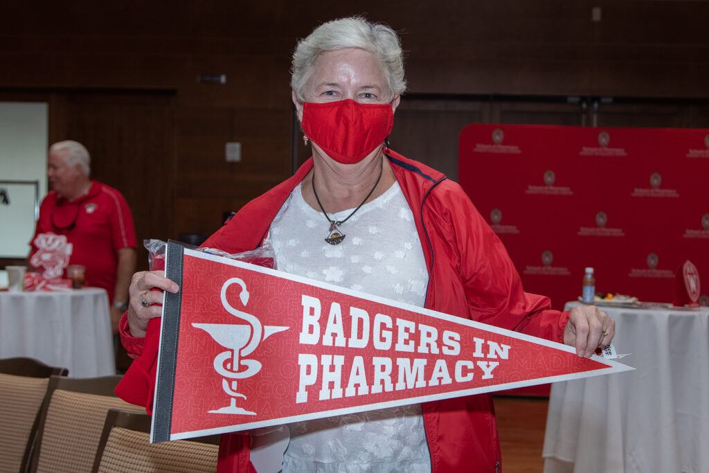 School of Pharmacy Alumni Tailgate Party 2021 SoP alumni holding up "Badgers in Pharmacy" prop