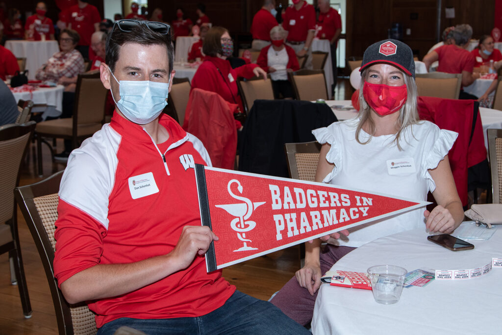 School of Pharmacy Alumni Tailgate Party 2021 Alumni sitting at table with badger merch