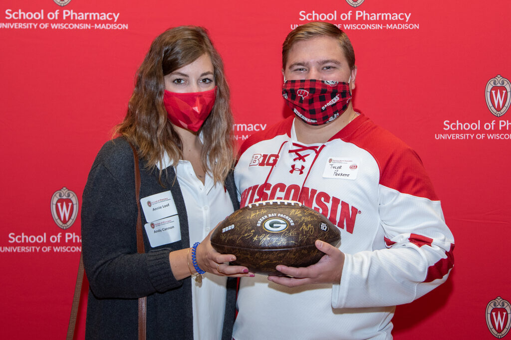 School of Pharmacy Alumni Tailgate Party 2021 Alumni holding signed Greenbay Packers football
