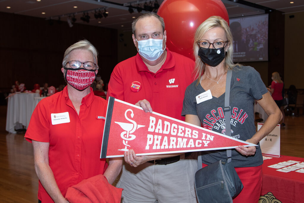 School of Pharmacy Alumni Tailgate Party 2021 Alumni event coordinators holding up "Badgers in Pharmacy" prop