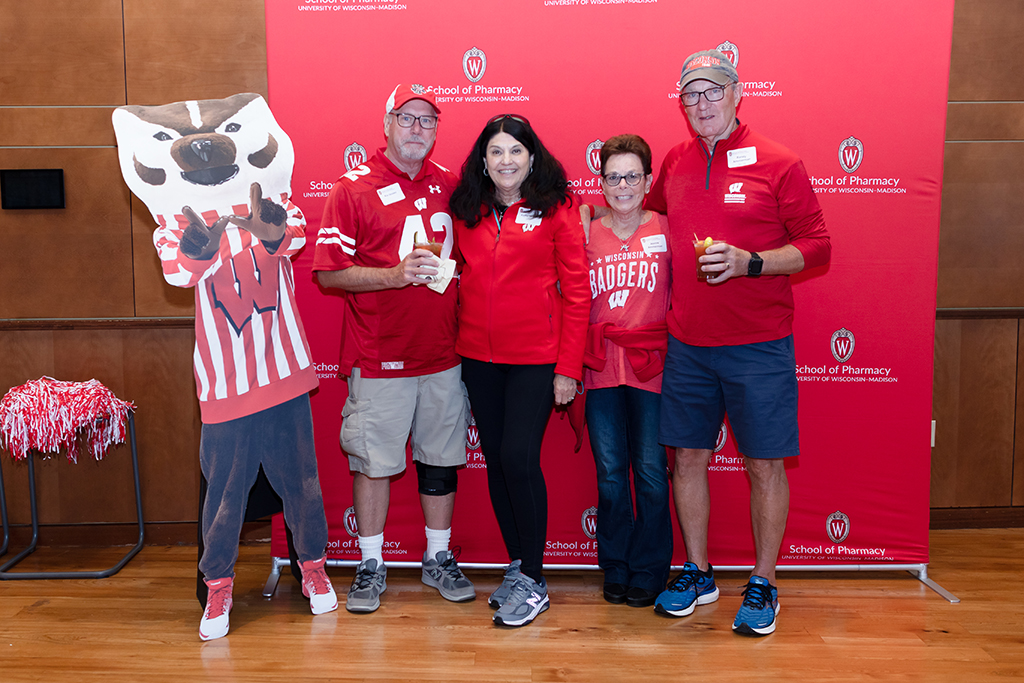 UW–Madison School of Pharmacy 2024 Alumni Tailgate and Watch Party Kie and Kathy Janzen with Randy and Jeanne Ammerman and a cardboard cutout of Bucky