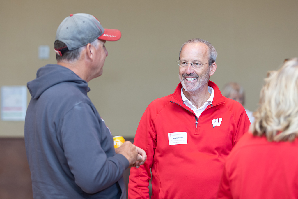 UW–Madison School of Pharmacy 2024 Alumni Tailgate and Watch Party Dave Mott smiles while speaking with an attendee