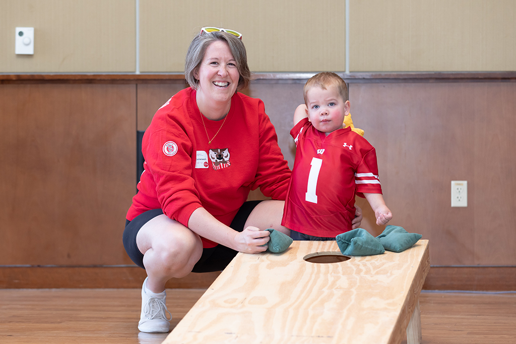 UW–Madison School of Pharmacy 2024 Alumni Tailgate and Watch Party Patti Thornwell plays bag toss with her toddler