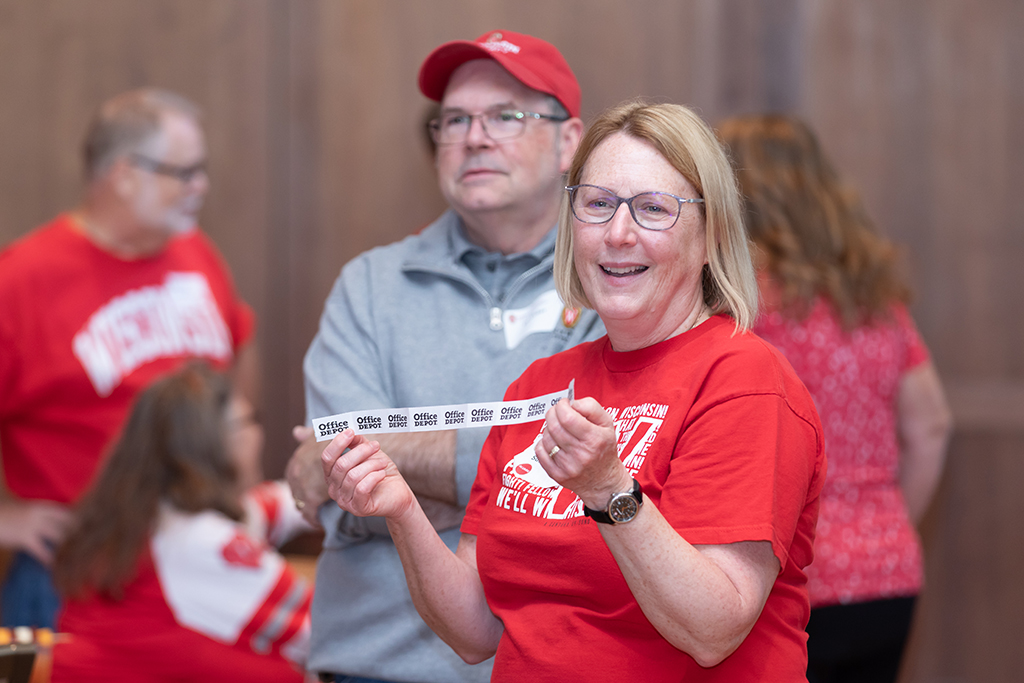 UW–Madison School of Pharmacy 2024 Alumni Tailgate and Watch Party A woman in a red T-shirt holds raffle tickets and smiles
