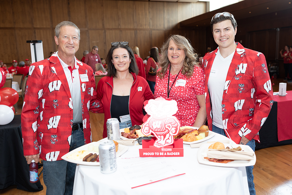 UW–Madison School of Pharmacy 2024 Alumni Tailgate and Watch Party Michael, Denise, Ellie, and Tim Kachel smile for a photo at a table with plates of food