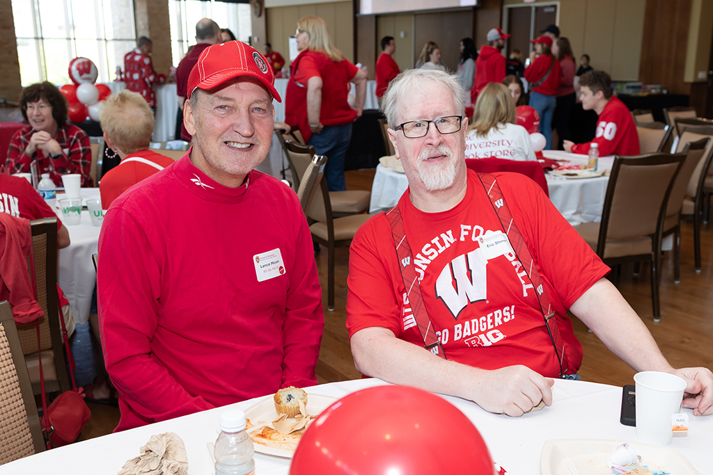 UW–Madison School of Pharmacy 2024 Alumni Tailgate and Watch Party Lance Moran and Eric Stoner smile for a photo while seated at a table