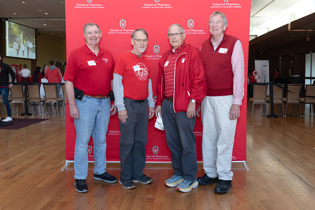 UW–Madison School of Pharmacy 2024 Alumni Tailgate and Watch Party Russ Jensen, David Duehring, Steve Craw, and Larry Lee pose for a photo in front of the red School of Pharmacy background