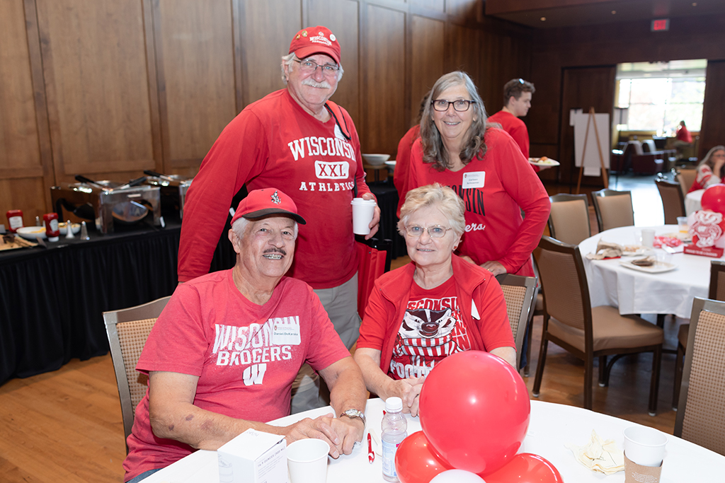UW–Madison School of Pharmacy 2024 Alumni Tailgate and Watch Party A group of attendees smile for a photo while seated at a table