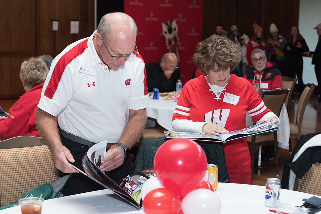 School of Pharmacy Alumni Tailgate Party 2023 Alumni looking through yearbooks