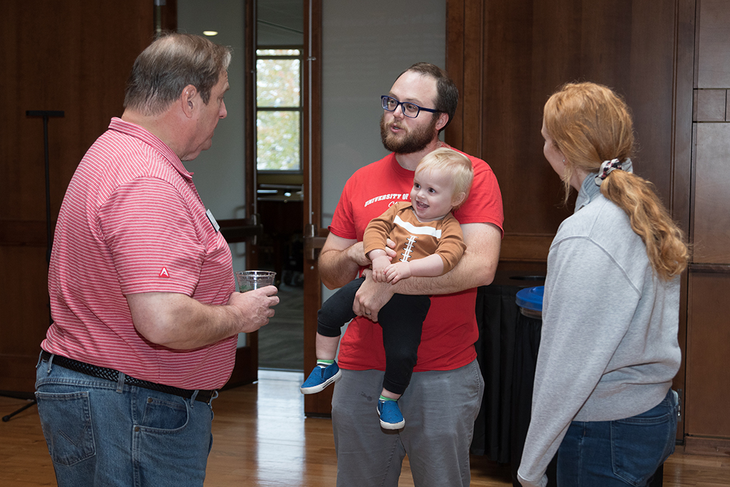 School of Pharmacy Alumni Tailgate Party 2023 Alumni holding young child talking with Dean Steve Swanson and another