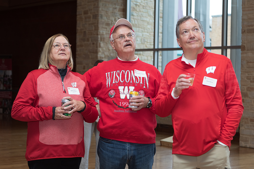 School of Pharmacy Alumni Tailgate Party 2023 Three alumni standing and looking up at something out of view