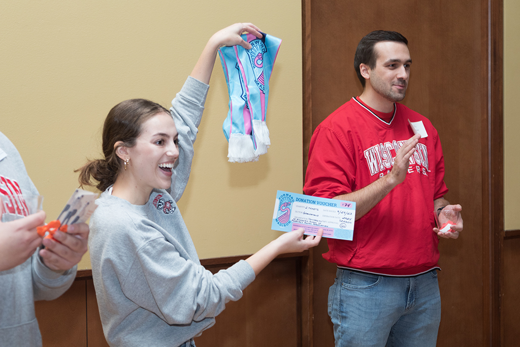 School of Pharmacy Alumni Tailgate Party 2023 Student holding up donation voucher for raffle