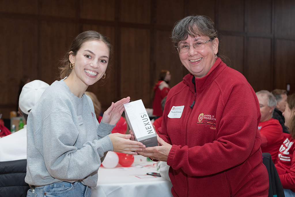 School of Pharmacy Alumni Tailgate Party 2023 Student delivering H2GO Nexus water bottle to raffle winner
