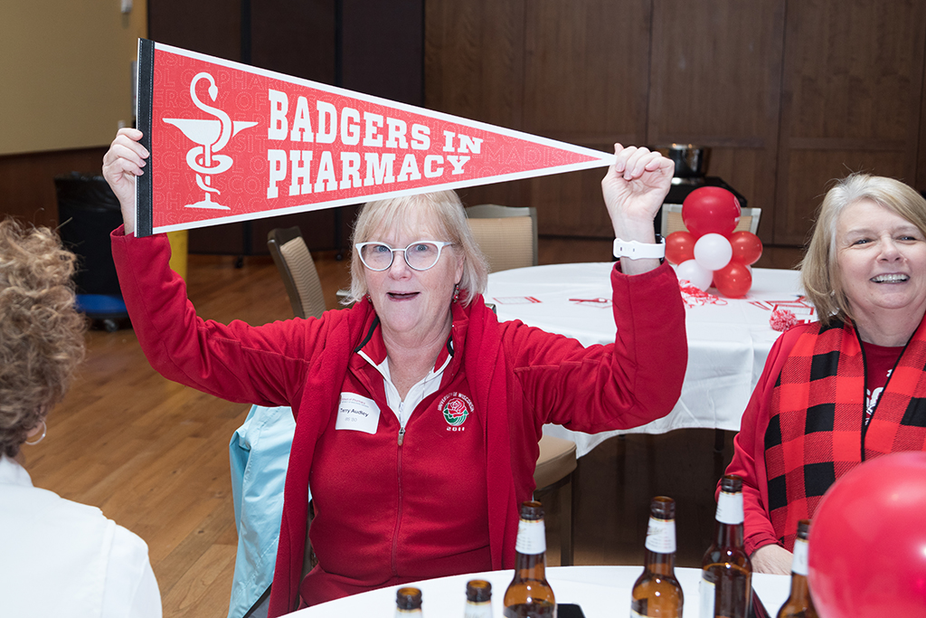School of Pharmacy Alumni Tailgate Party 2023 Alumnus holding up "Badgers in Pharmacy" flag