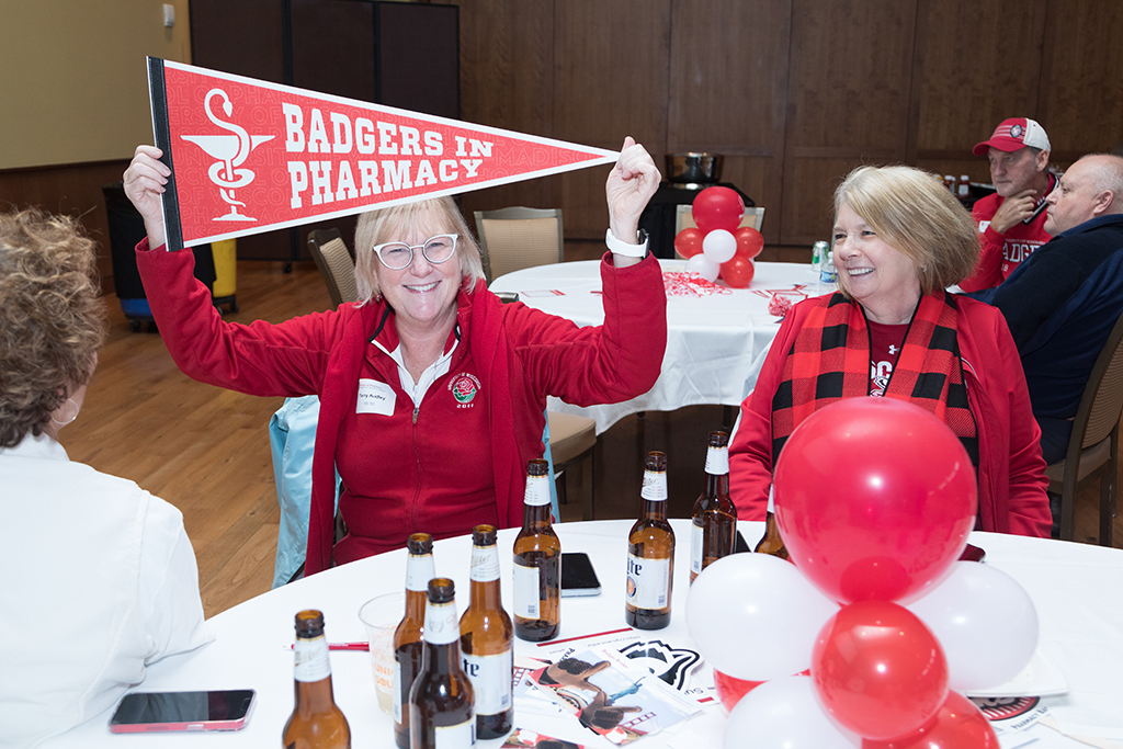 School of Pharmacy Alumni Tailgate Party 2023 Alumnus holding up "Badgers in Pharmacy" flag