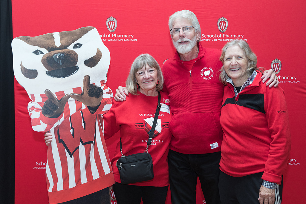 School of Pharmacy Alumni Tailgate Party 2023 Alumni stand arm-in-arm with Bucky Badger cutout