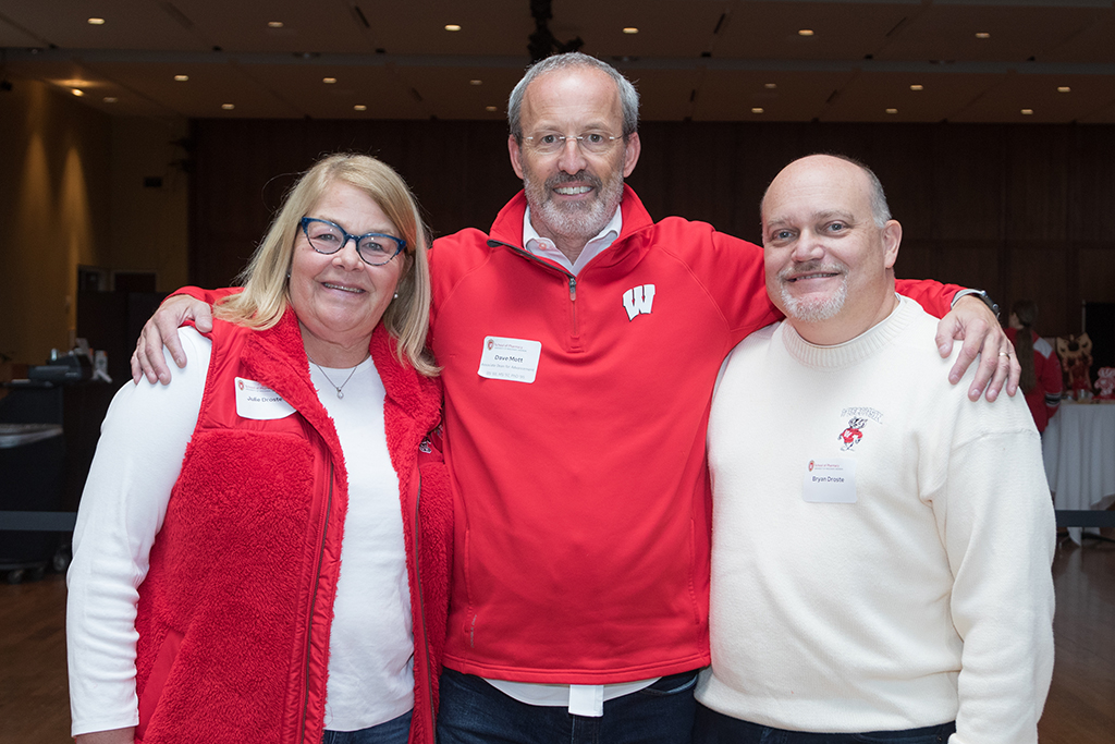 School of Pharmacy Alumni Tailgate Party 2023 Dave Mott with his arms around School of Pharmacy donors Bryan and Julie Droste