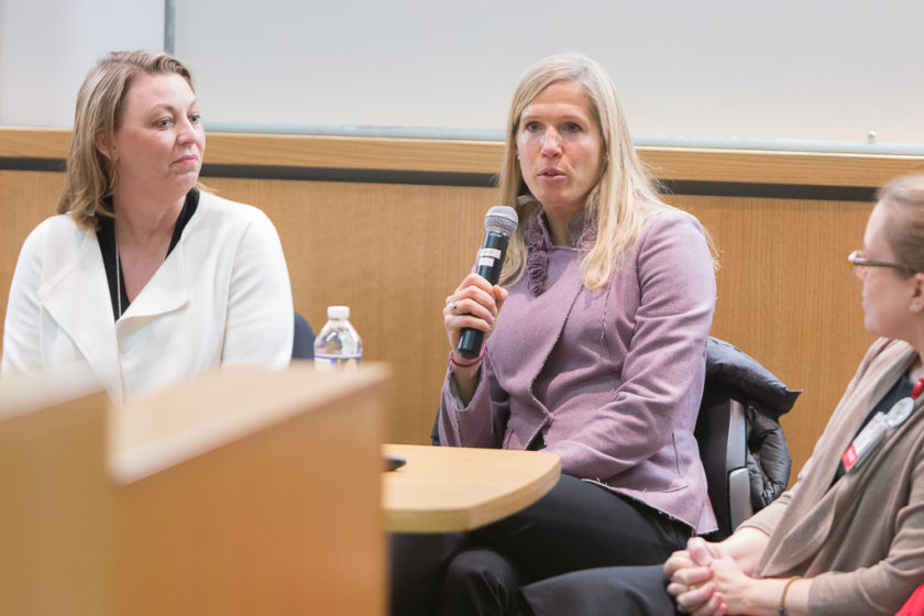 Woman on panel speaking into a microphone during career development day