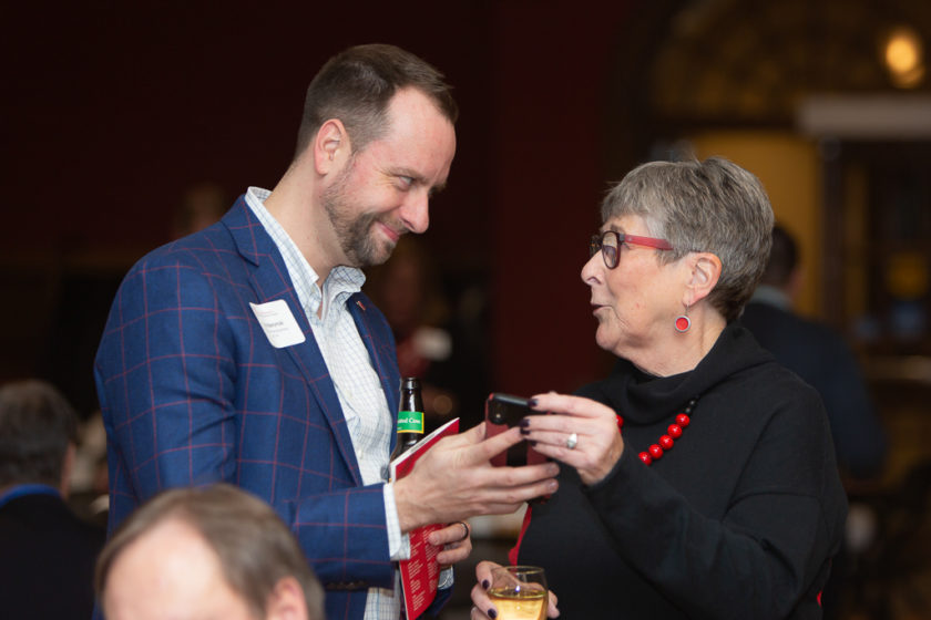 phar110819_118 Man helping older woman with her phone at citations of merit dinner