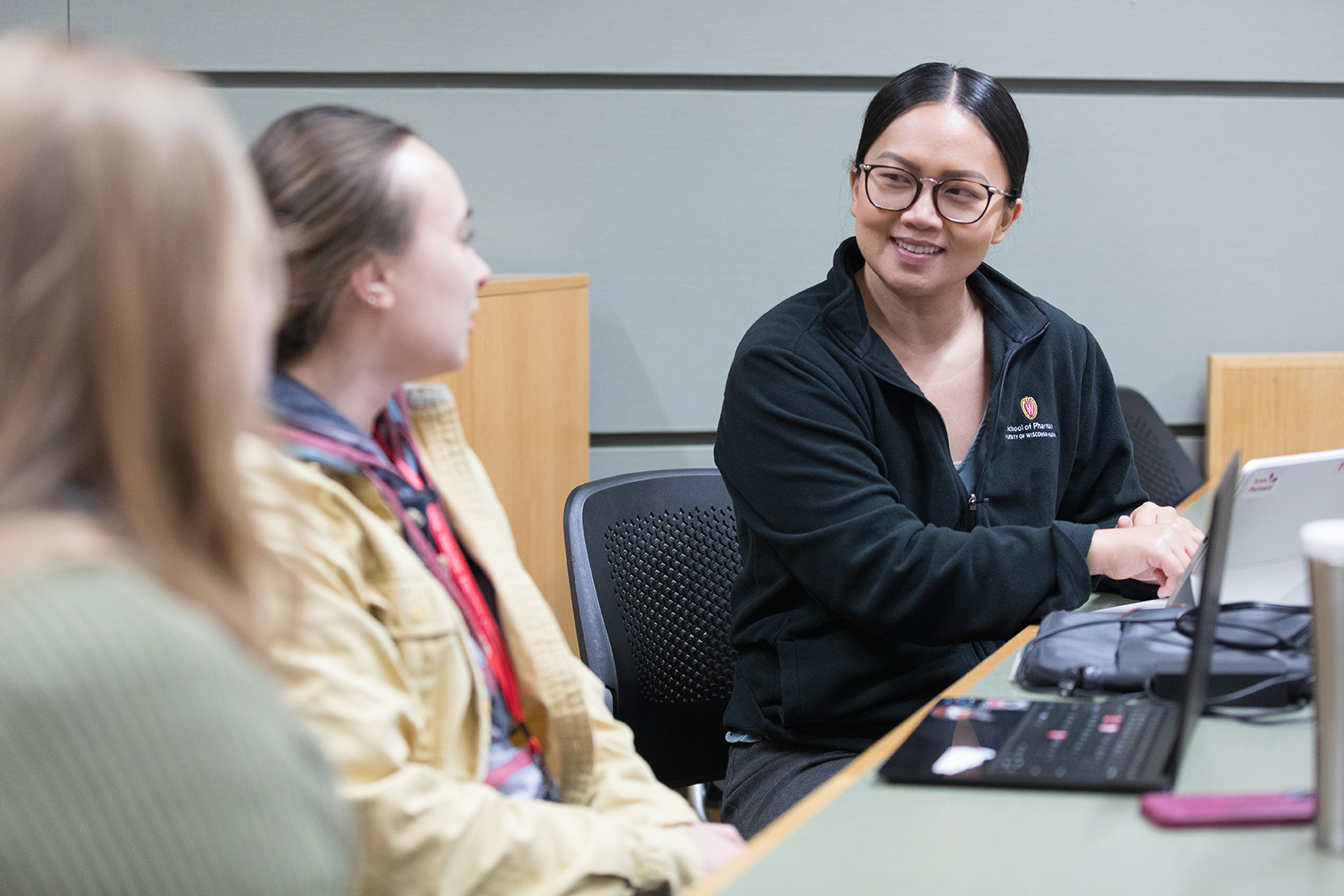 Three female PharmD students speaking in a lecture hall.