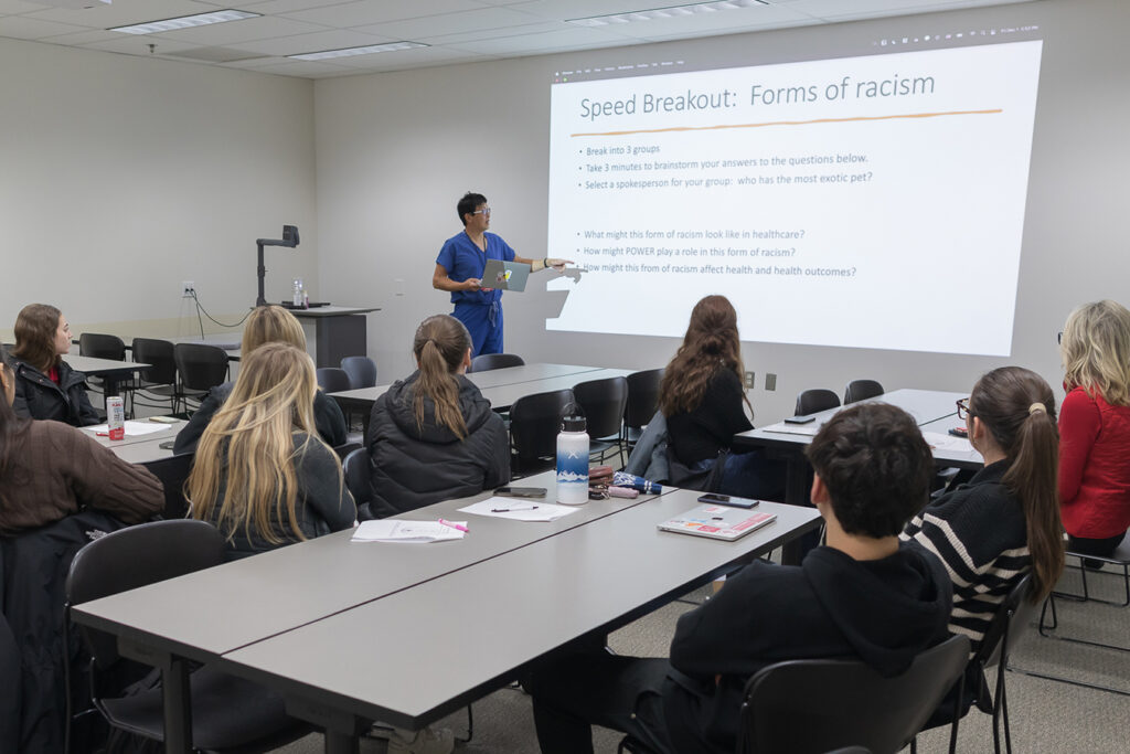 SoP Lecture: Cultivating Belonging in Pharmacy (December 1, 2023) Jonas Lee speaks in front of a presentation projected on the wall.