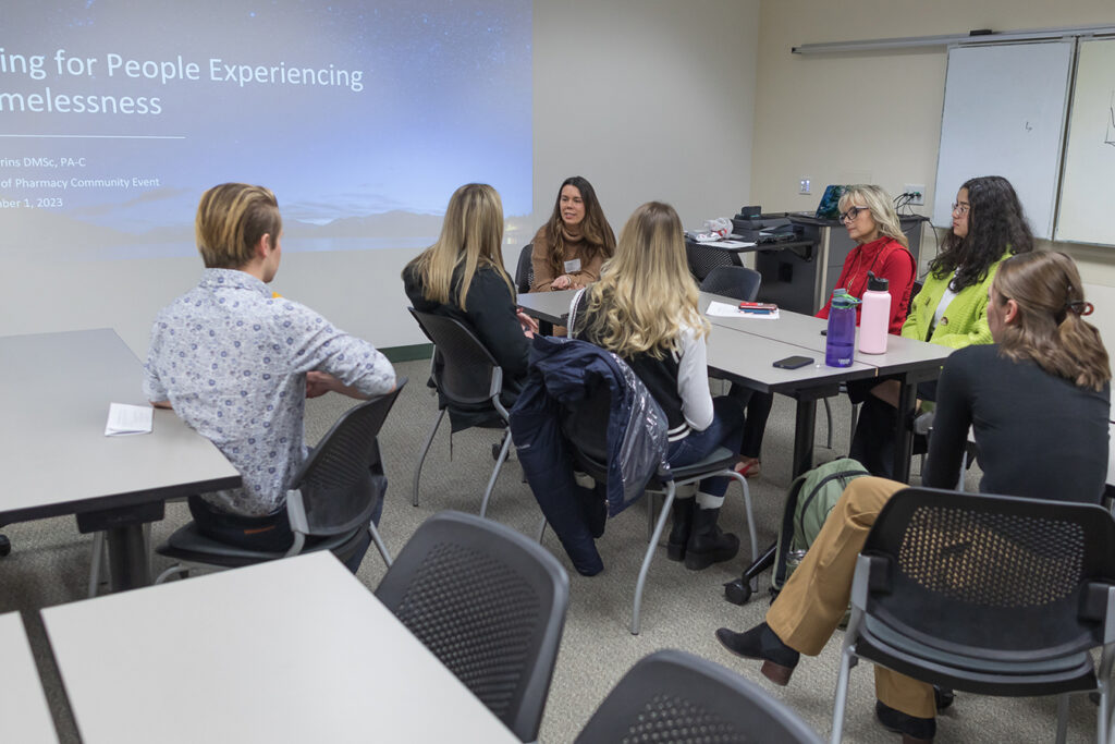 SoP Lecture: Cultivating Belonging in Pharmacy (December 1, 2023) Amy Parins seated, speaking with a table of students