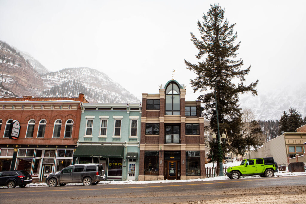 real-life-photographs-02 An exterior photo of the Ouray Alchemist with snowy mountains in the background.