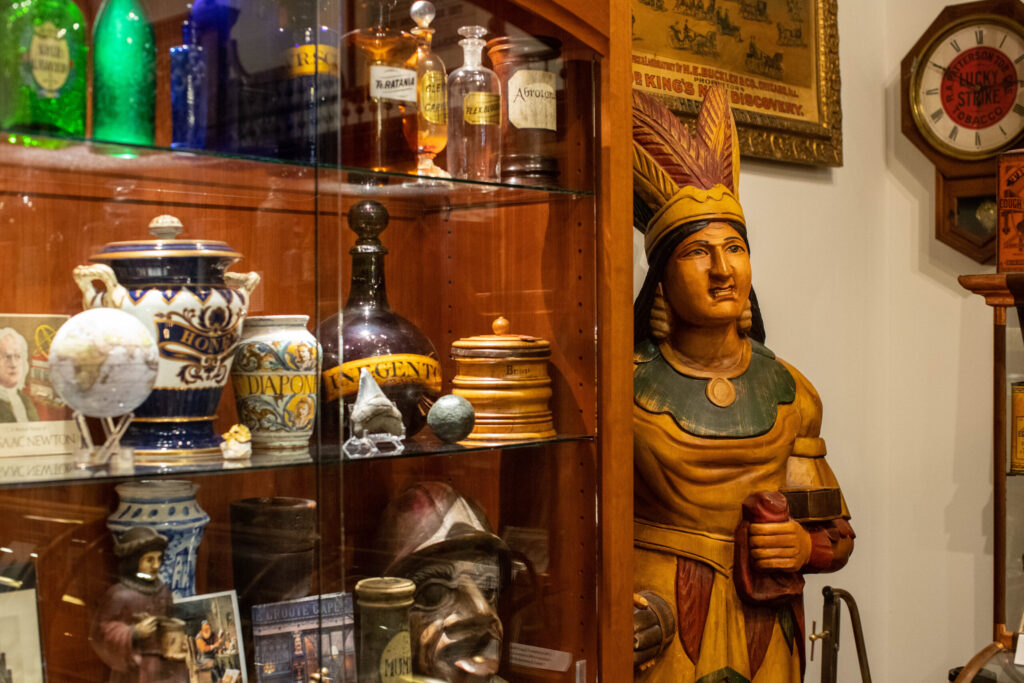 real-life-photographs-19 A glass case filled with ceramic and glass jars and a wooden carving of a native woman with a headdress on.