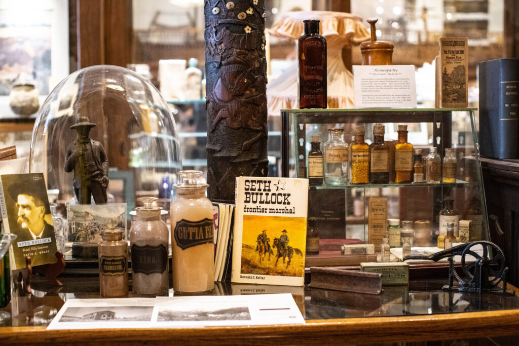 real-life-photographs-45 A glass display cabinet with glass prescription bottles and books by Seth Bullock, frontier marshal.